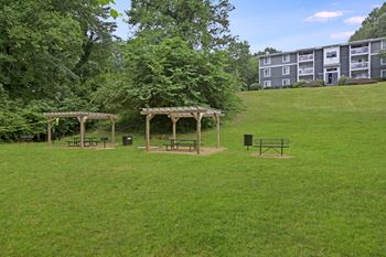A grassy field with a gazebo and picnic tables.